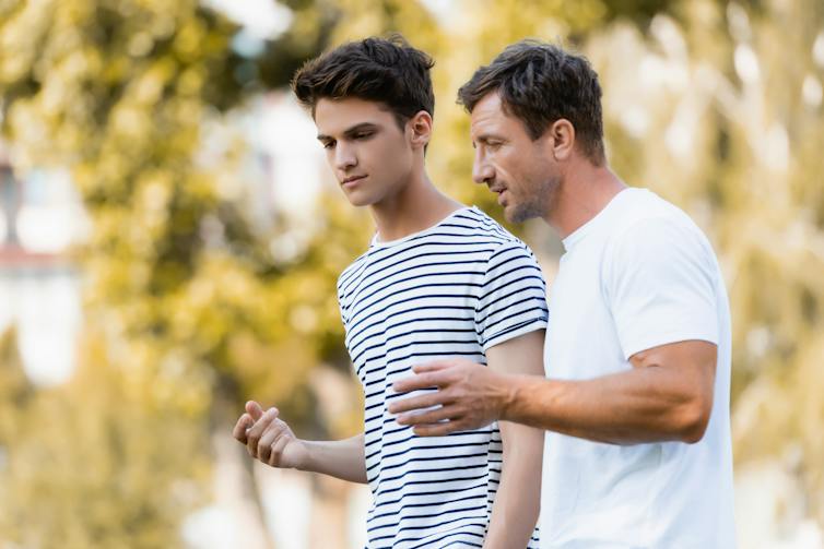 Un homme et un adolescent marchent et se parlent