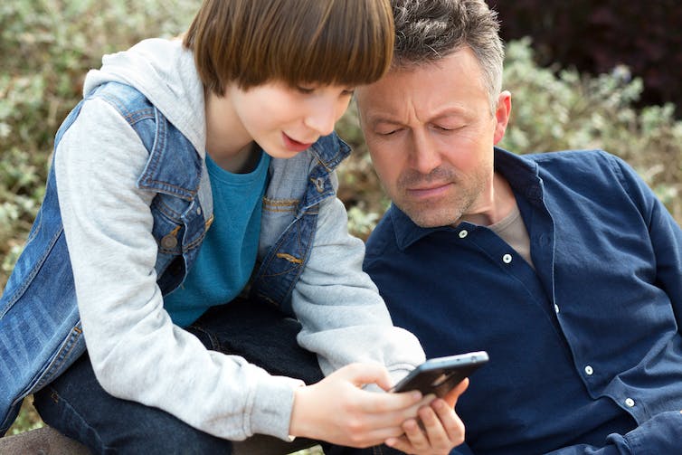 Père et fils regardant un téléphone portable