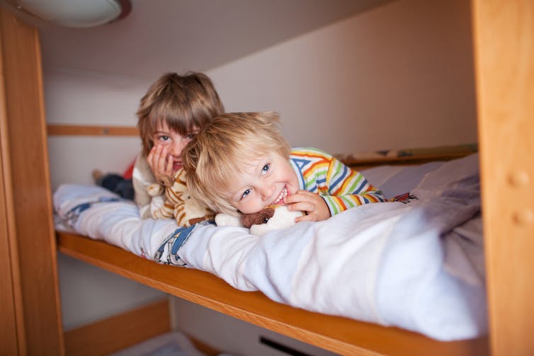 Deux enfants sortent d'un lit superposé.