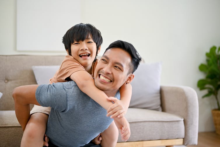 Un homme asiatique jouant avec un jeune garçon. Les deux sourient