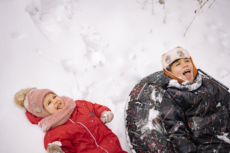 Deux enfants vus jouer dans la neige.