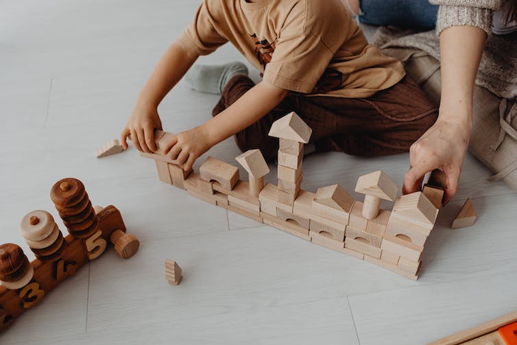 Un adulte et un enfant jouent avec des blocs de bois.