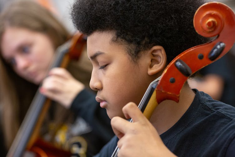 Un enfant préadolescent jouant d'un instrument à cordes.