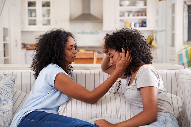 Une mère réconfortant un adolescent bouleversé sur un canapé