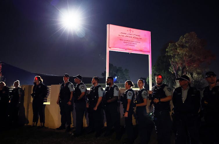 La police se tient devant la clôture d’une église.