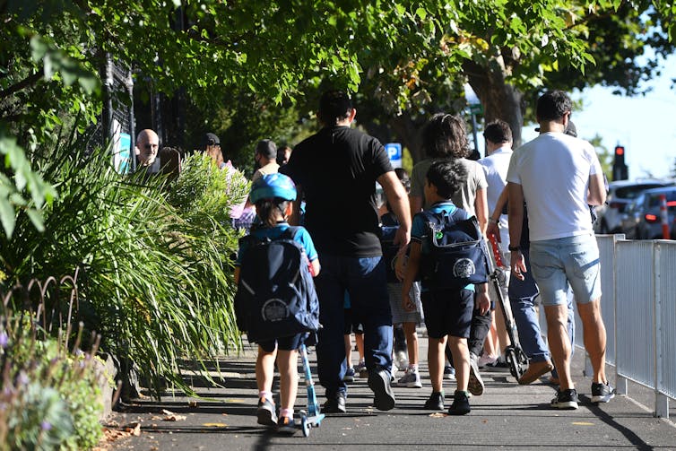Parents et enfants marchent le long du sentier. Un enfant est sur une trottinette.