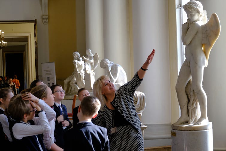 Une classe d'enfants regarde une statue nue.