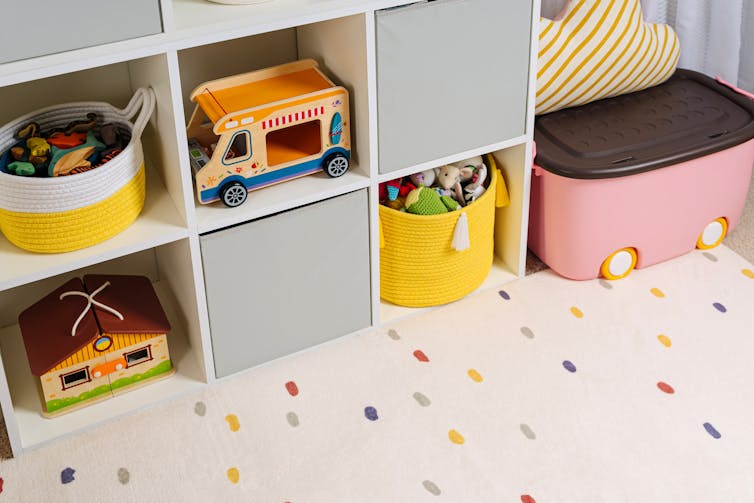 Une étagère avec des jouets et des boîtes soigneusement rangés.