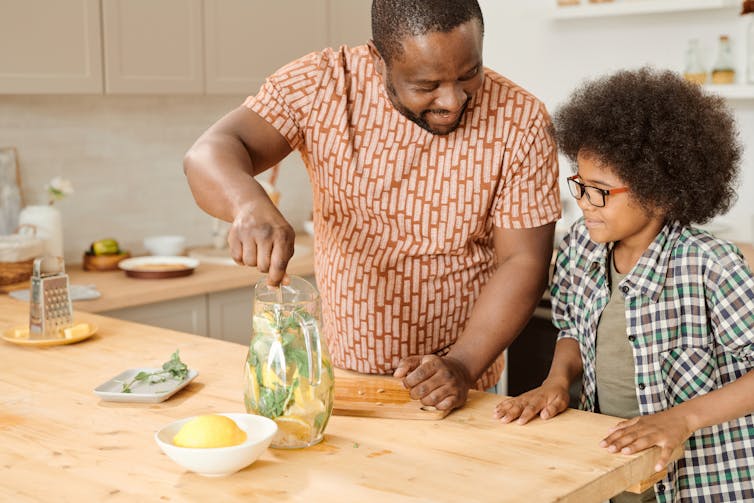 homme et enfant au comptoir de la cuisine préparant de la limonade