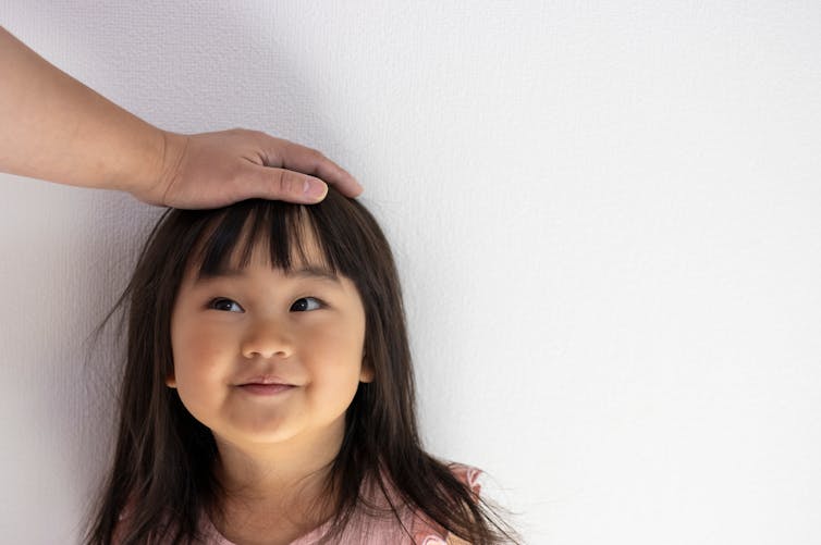 Un adulte tapote la tête d’une jeune fille.
