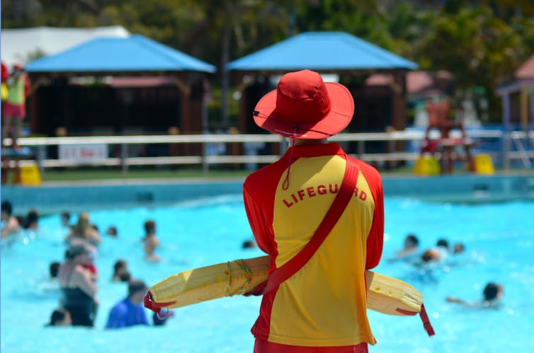 Un sauveteur surveille les nageurs dans une piscine publique.