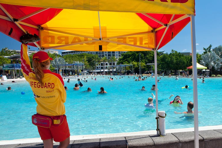 Un sauveteur regarde les nageurs dans une grande piscine.