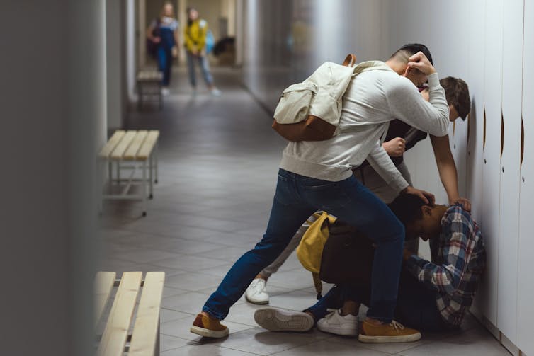 Un adolescent pousse un autre adolescent dans un casier dans une école