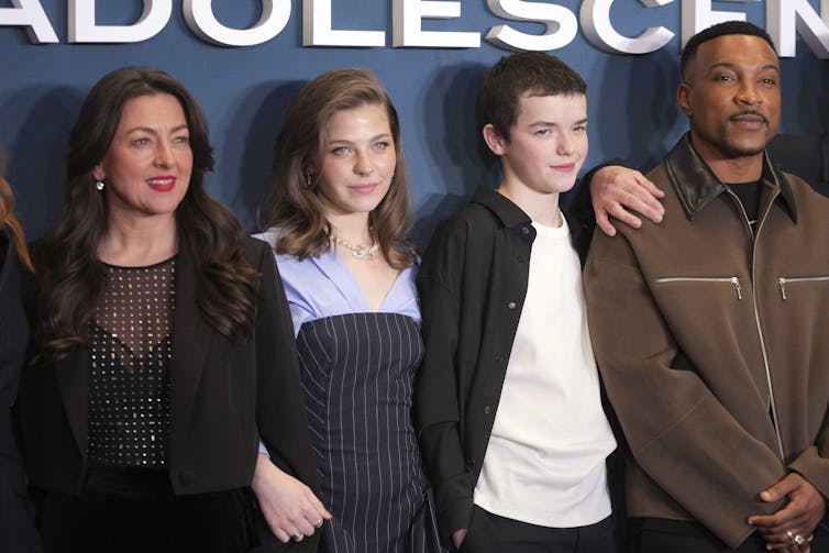 Quatre personnes ont posé sur une toile de fond bleue.