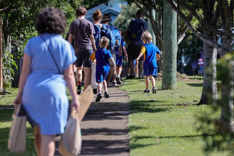 Les parents marchent avec des enfants en uniformes le long d'un sentier.