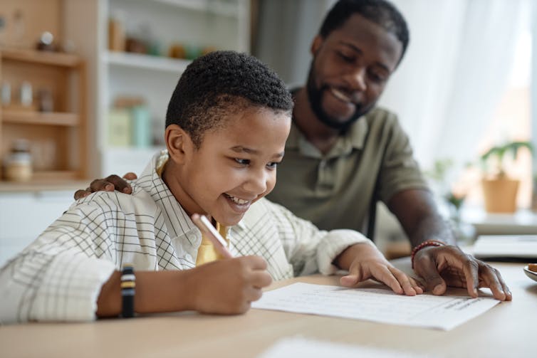 Homme et fils faisant des devoirs en souriant