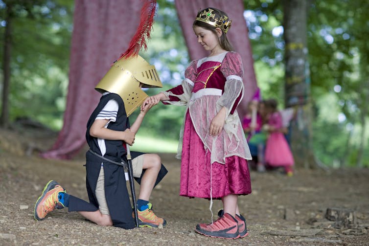 Un enfant habillé en chevalier prend la main d'un enfant vêtu de princesse.