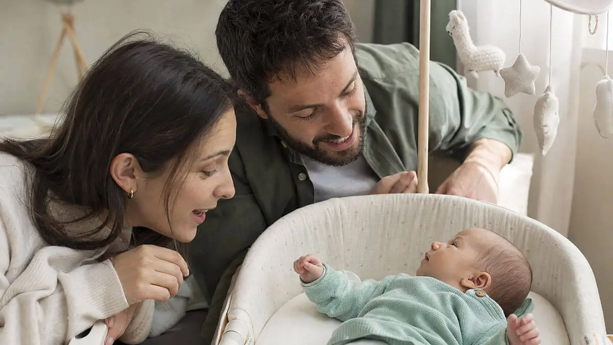 Soignant parlant à bébé devant le visage, bébé incline la tête en orientation vers le son, arrière-plan flou de la crèche, style photo