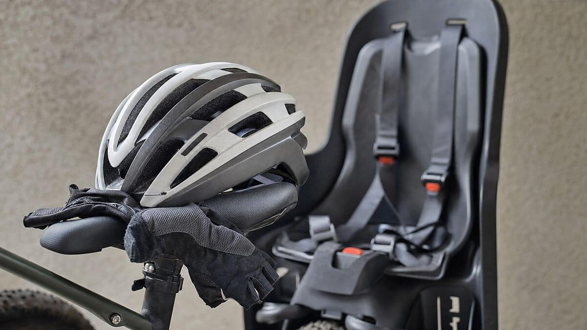 Garage extérieur à côté du vélo, liste de contrôle visuelle : mains vérifiant les freins et les verrous, casque d'enfant d'un côté, lumière chaude